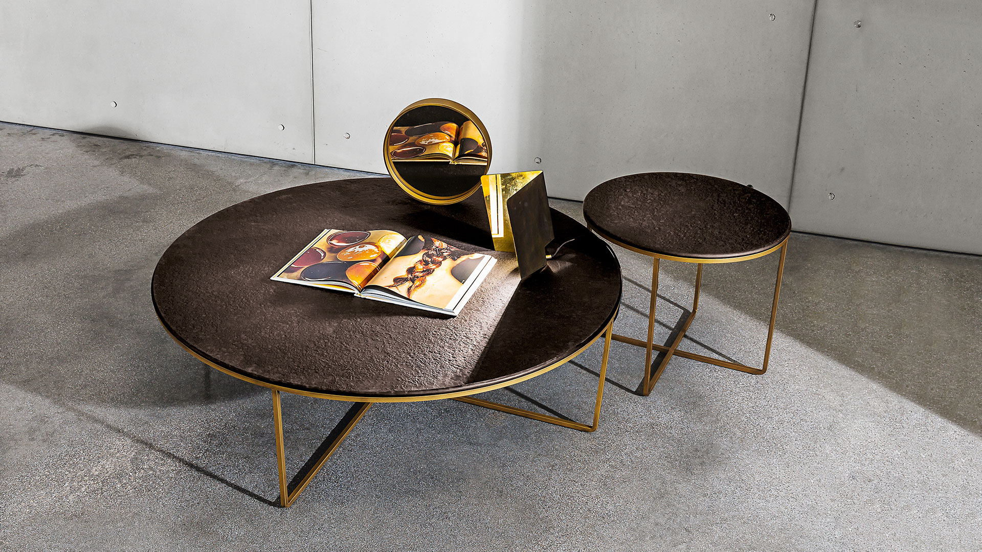 Due tavolini rotondi di dimensioni diverse con struttura in metallo colore ottone brunito e top in vetro materico bronzo