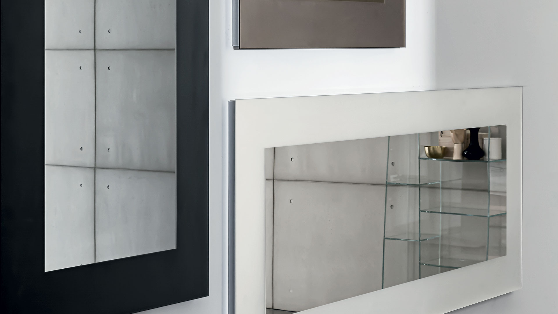 Due specchi da parete uno in posizione orizzontale con cornice larga in vetro bianca e uno verticale con cornice nera