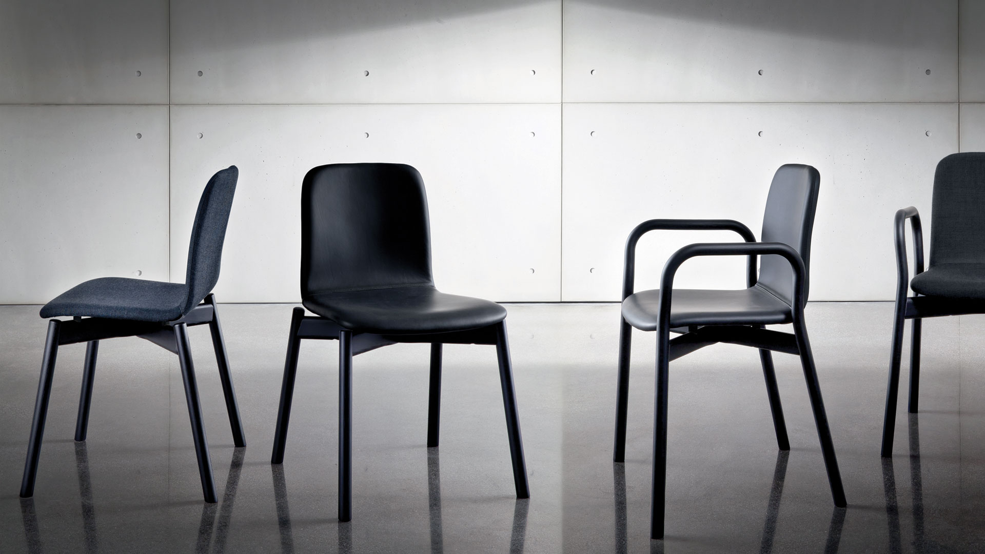 Due sedie con quattro gambe e struttura in frassino tinto nero rivestito in pelle nera e due sedie rivestite in tessuto nero