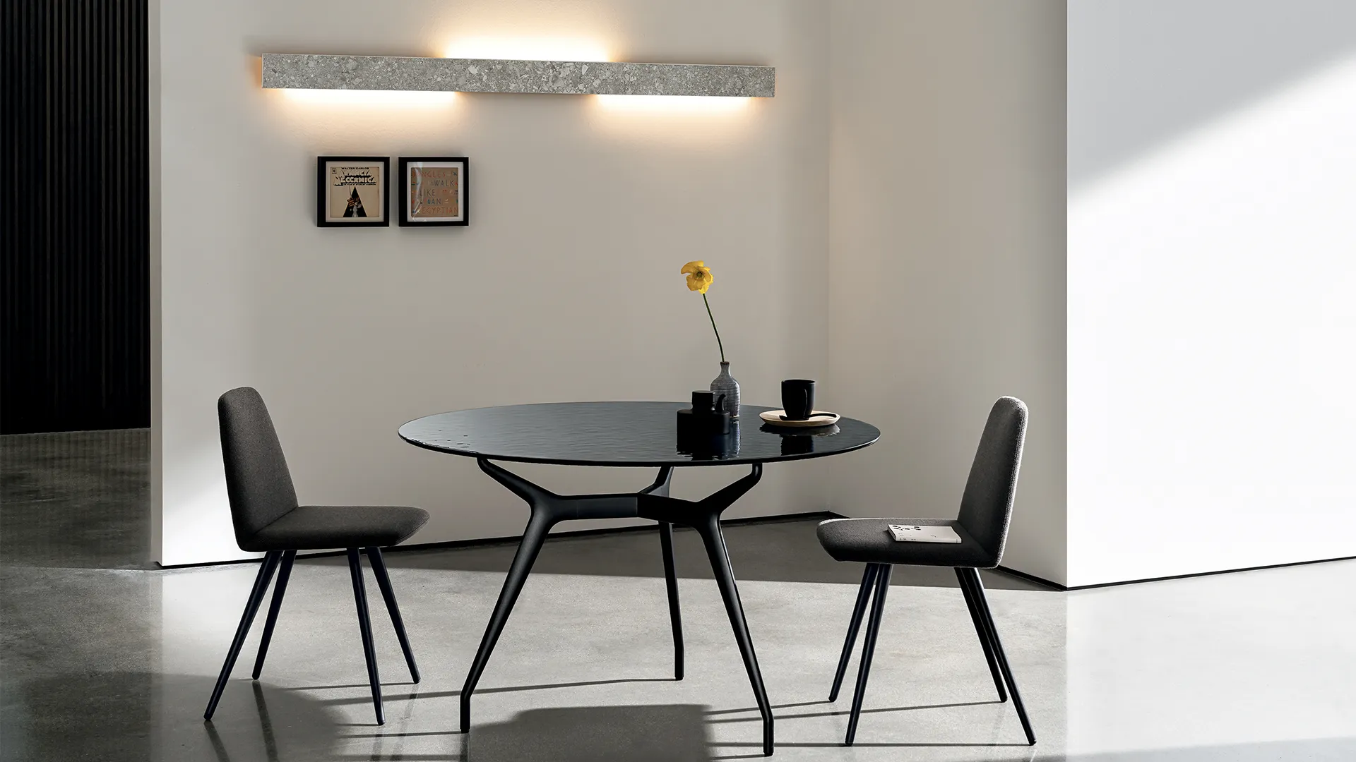 Tavolo di design dalla forma circolare con gambe e struttura in alluminio di colore nero e piano in smoke liquid glass