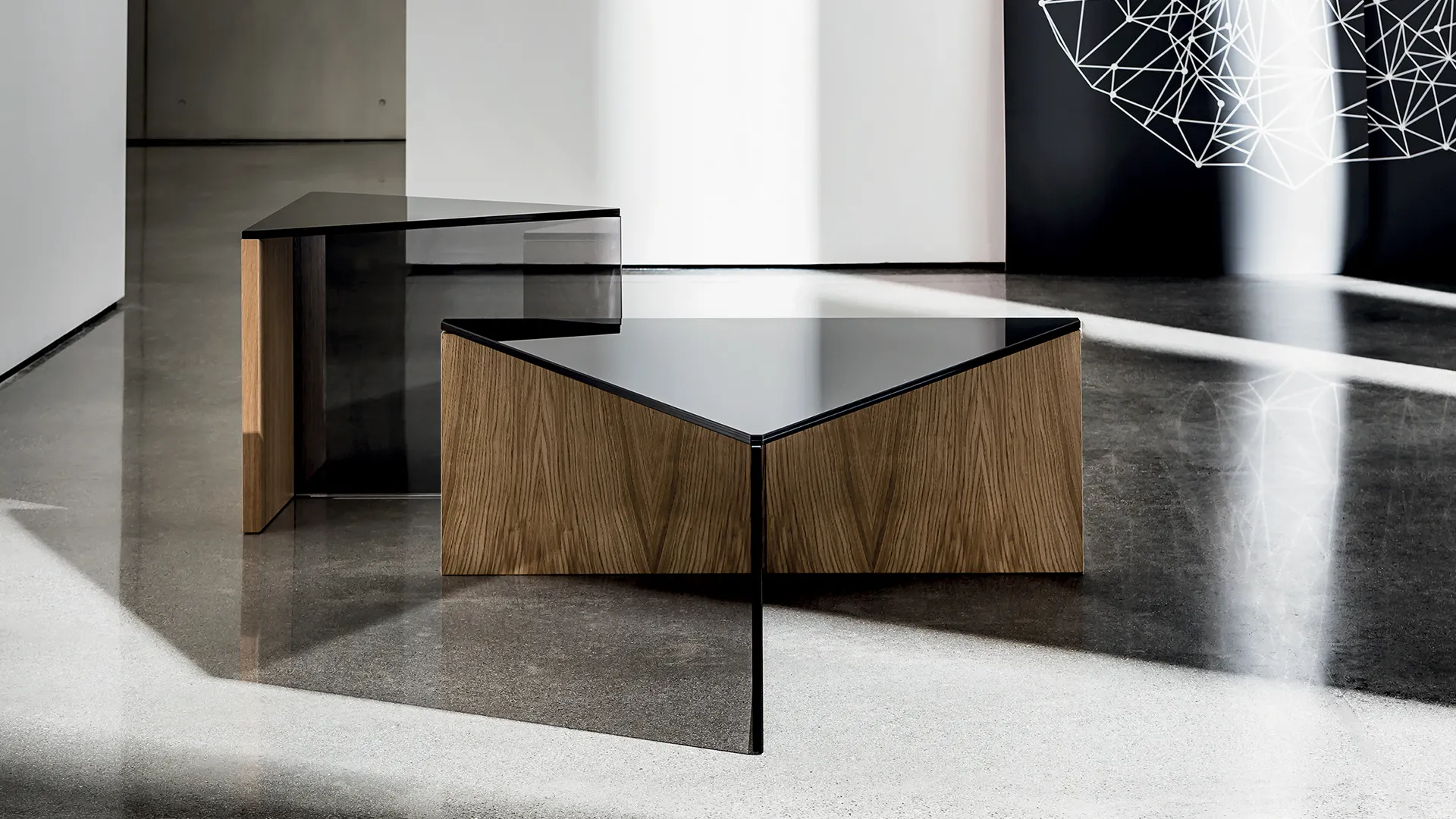 Tavolino dalla forma triangolare con base composta da elemento in legno noce canaletto ed elemento in vetro colore nero con piano in vetro nero
